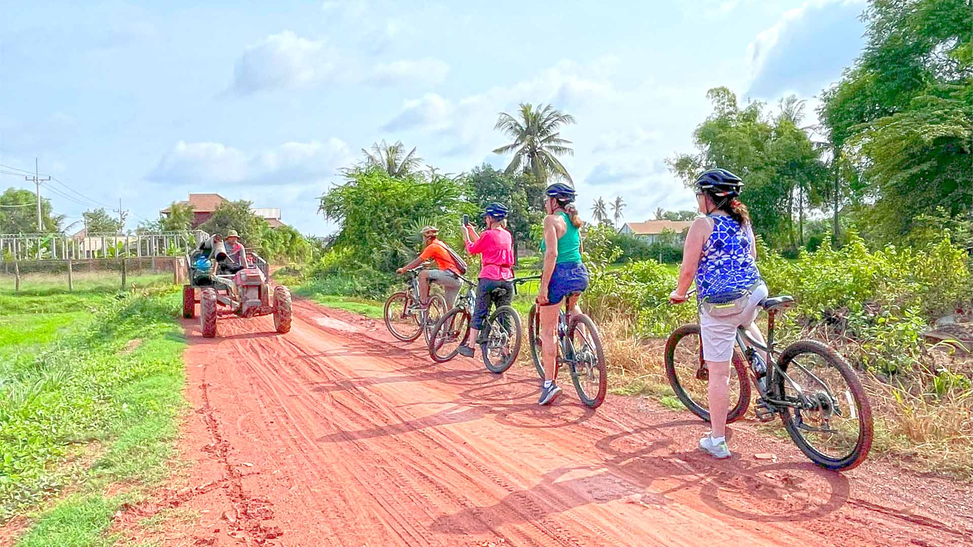 a group of people riding bikes on a dirt road